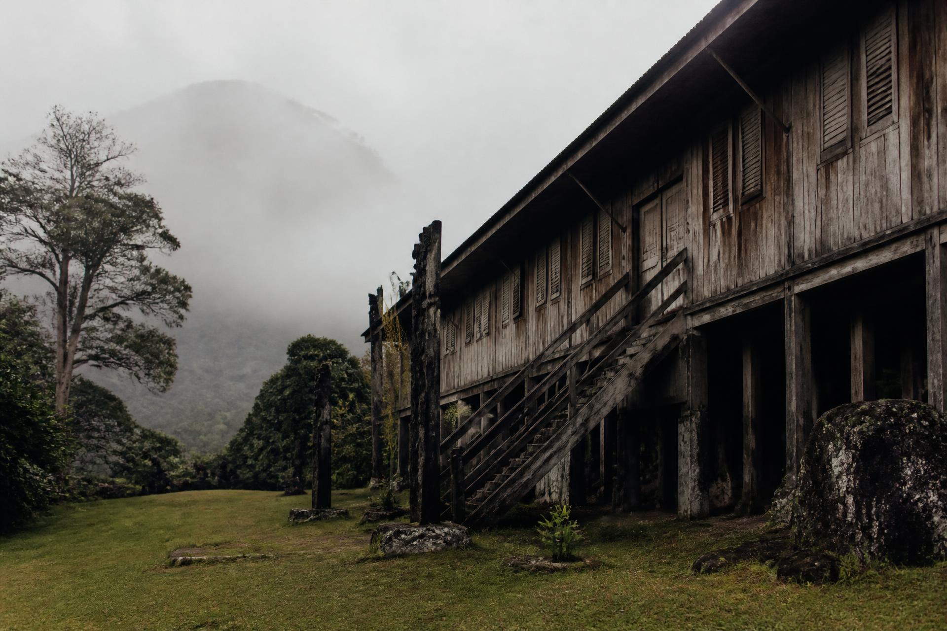 A weathered timber longhouse resting below misted mountains
